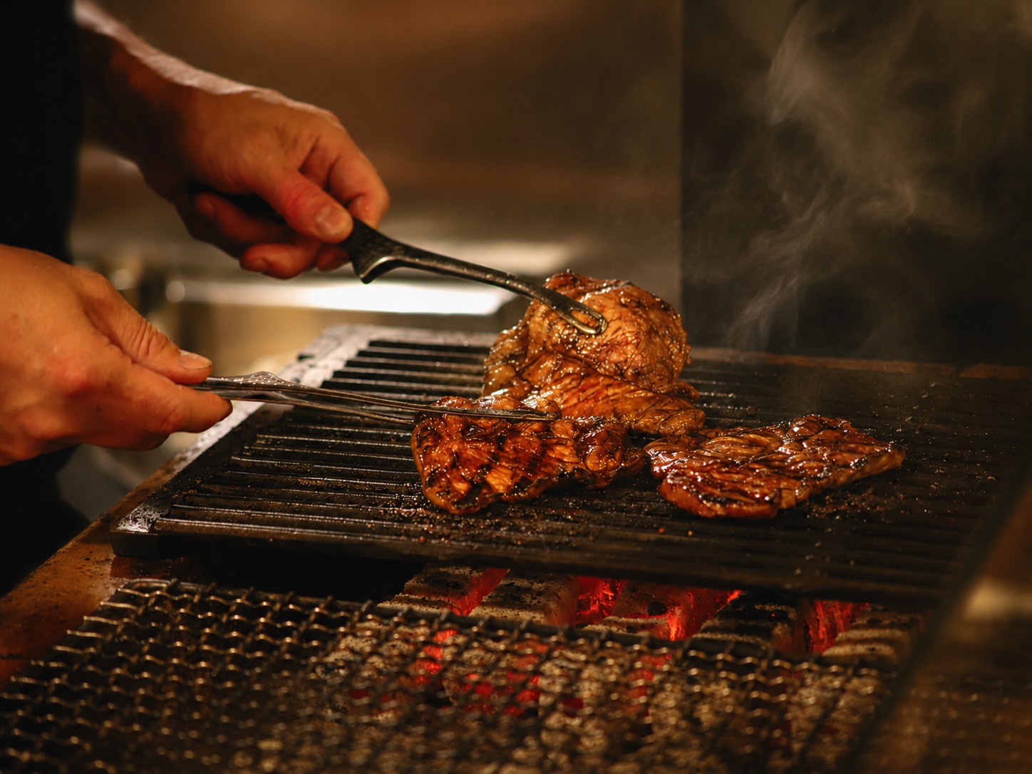 炭火で肉を焼き上げる店主の手元